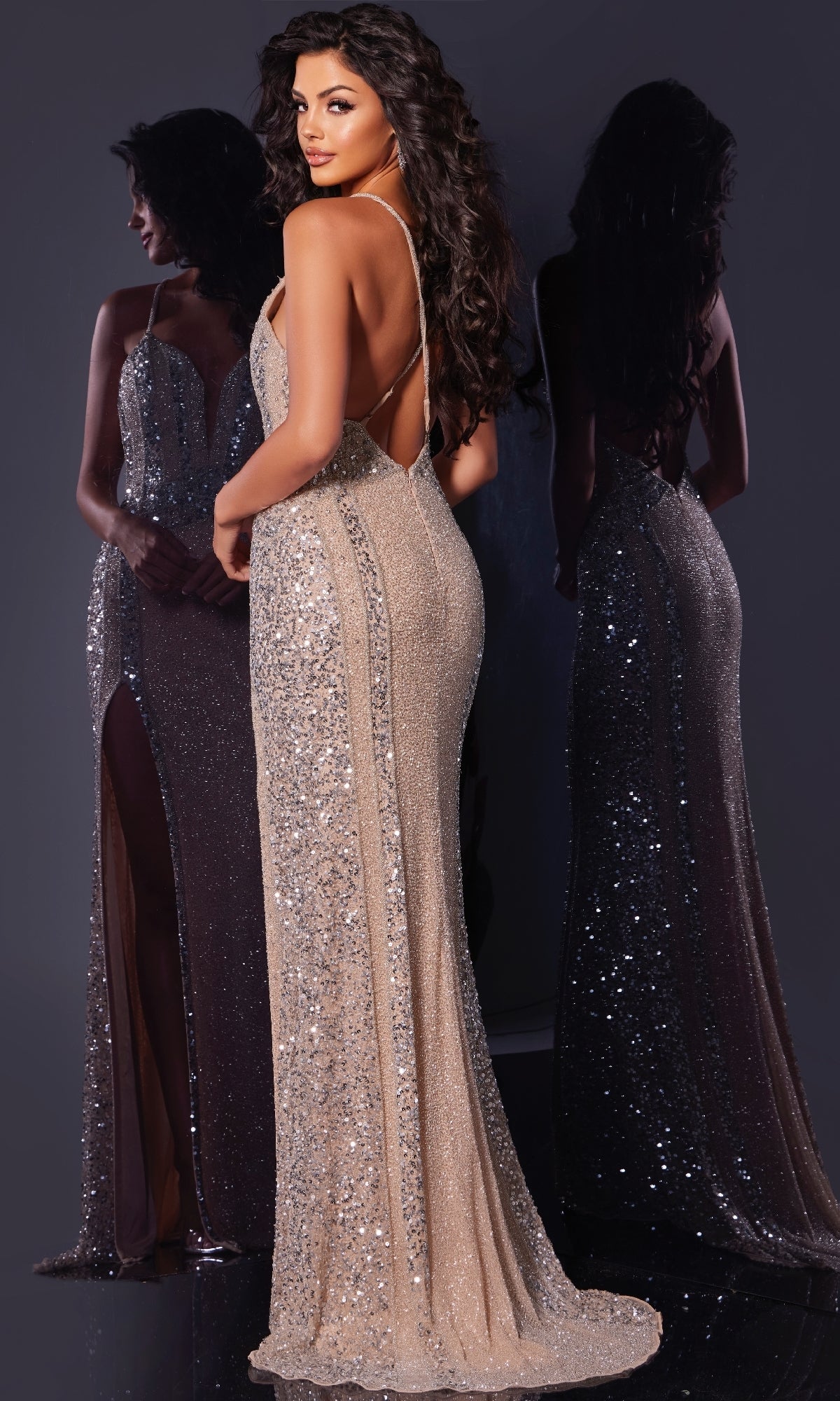 A woman in a sparkly, form-fitting Jovani 43918 long prom dress with a low back stands before a mirror, displaying both her back and the front of the gown in the reflection.